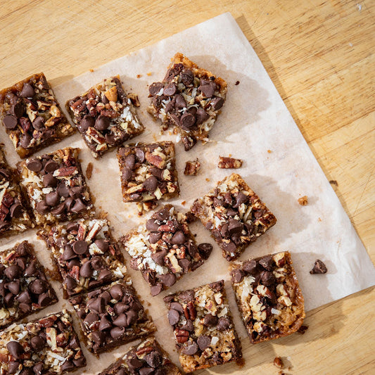 Bite size squares of chocolate hello Helen Bars scattered on a table.