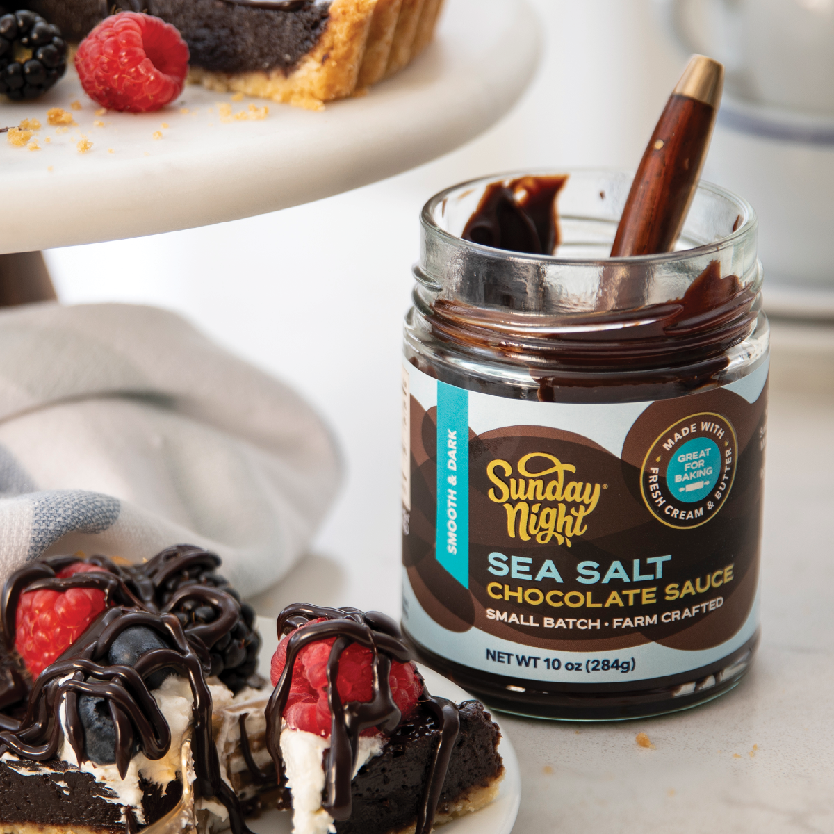 Sunday Night Sea Salt Chocolate Sauce is smooth, dark and delicious on raspberry chocolate tarts.